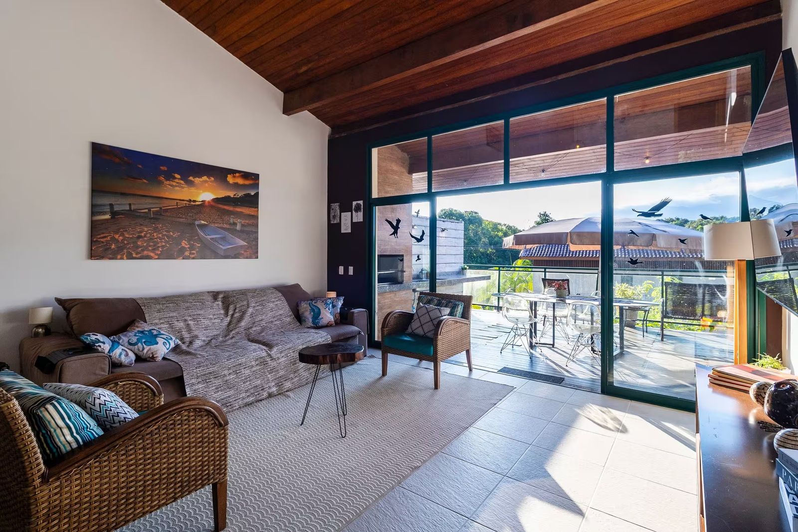 Sala com sofá e portas de vidro abertas para a varanda