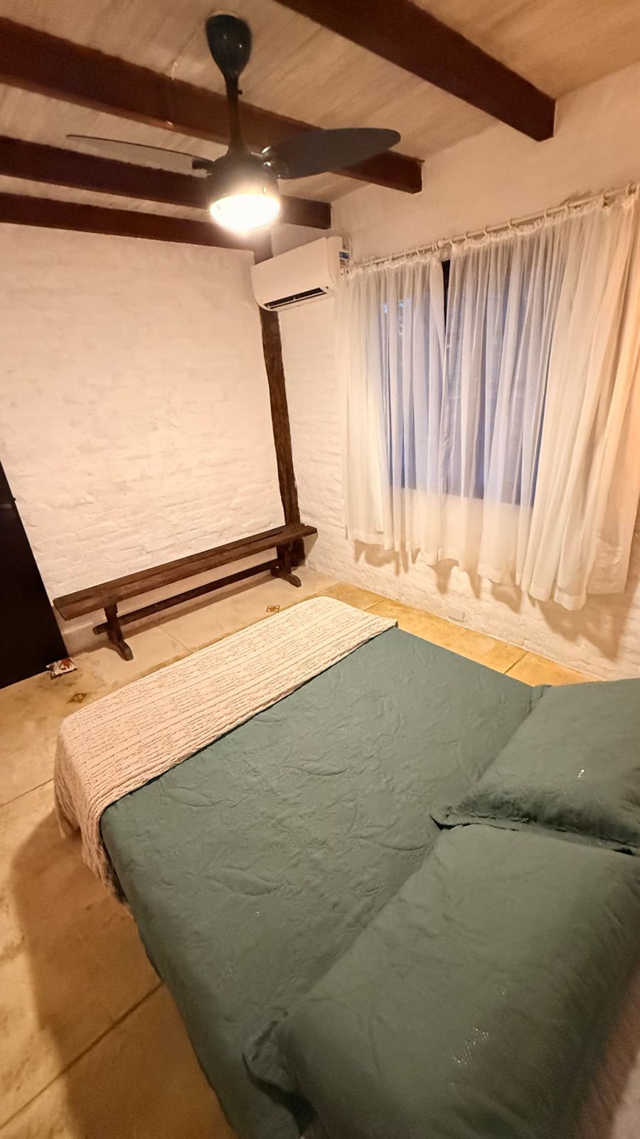 Cama com enxoval verde junto à janela