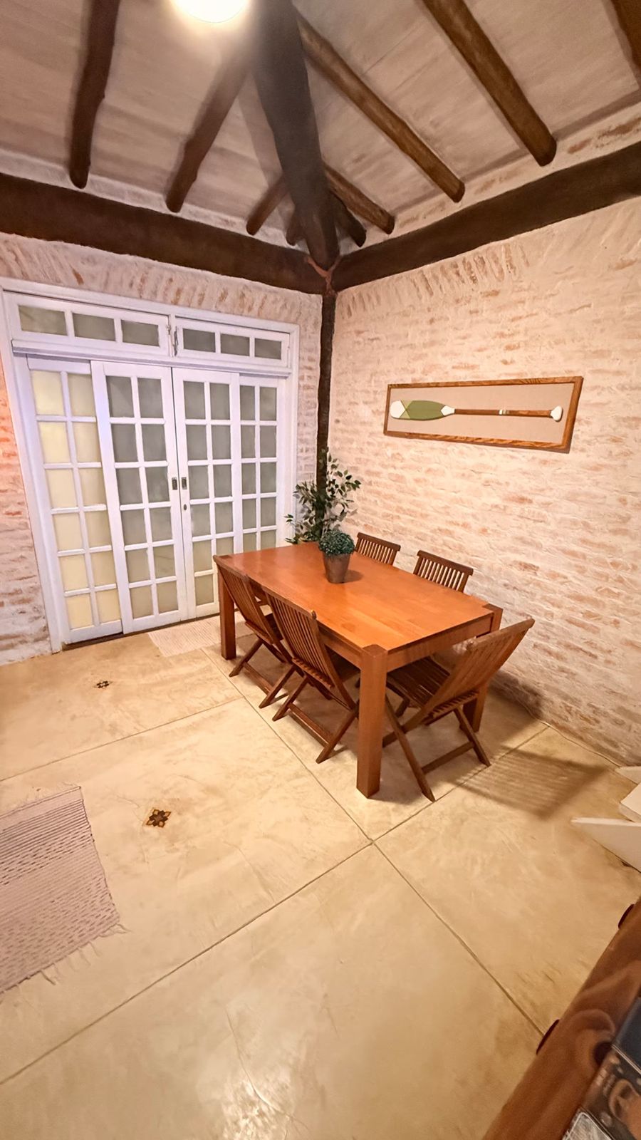 Sala com mesa de jantar, vigas de madeira e portas para fora