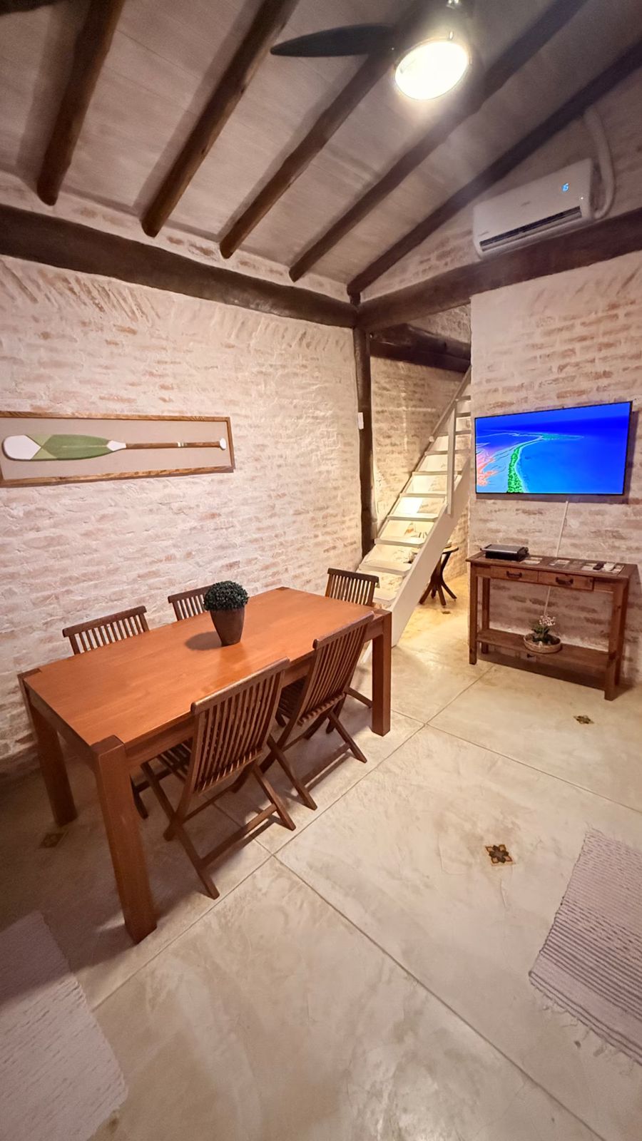 Mesa de jantar, TV e escada para o mezanino