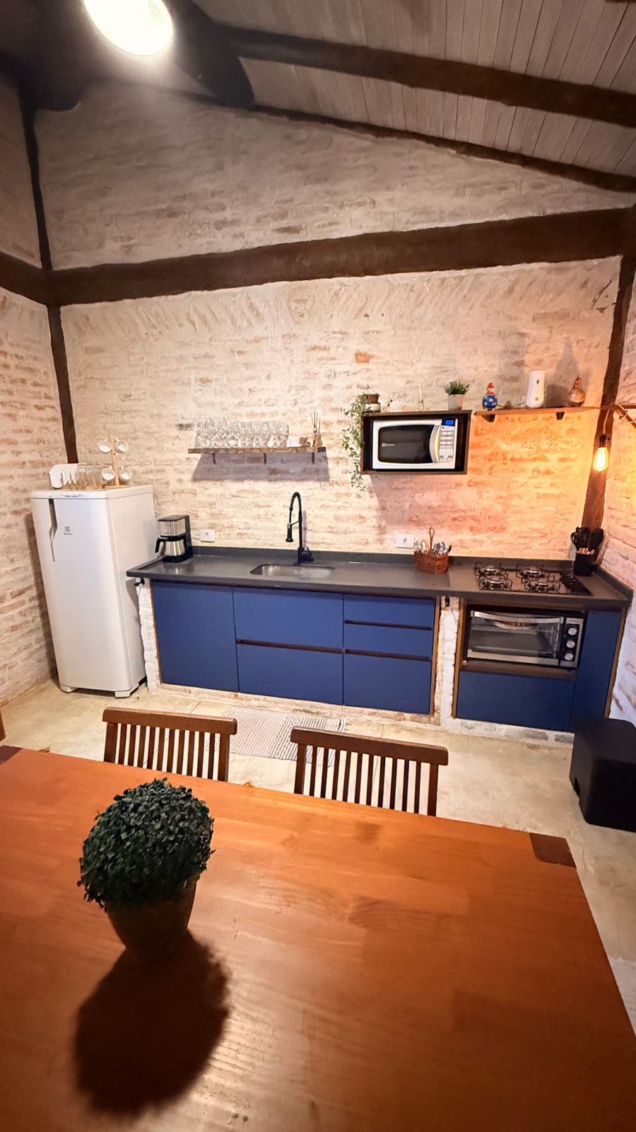 Cozinha com geladeira, micro-ondas e mesa
