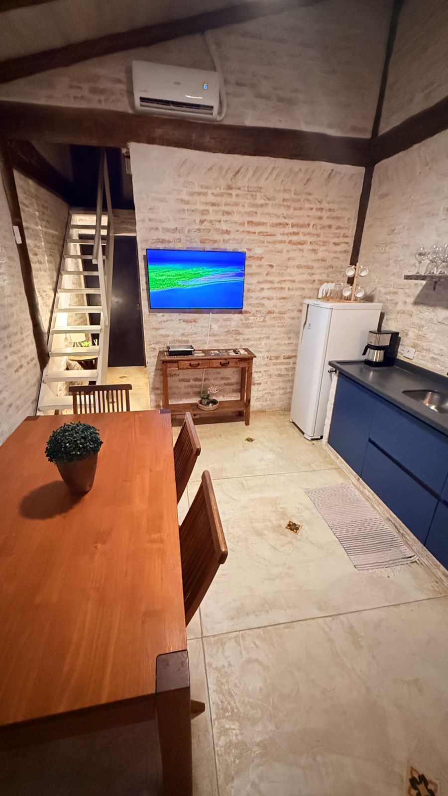 Sala com mesa, cozinha e TV