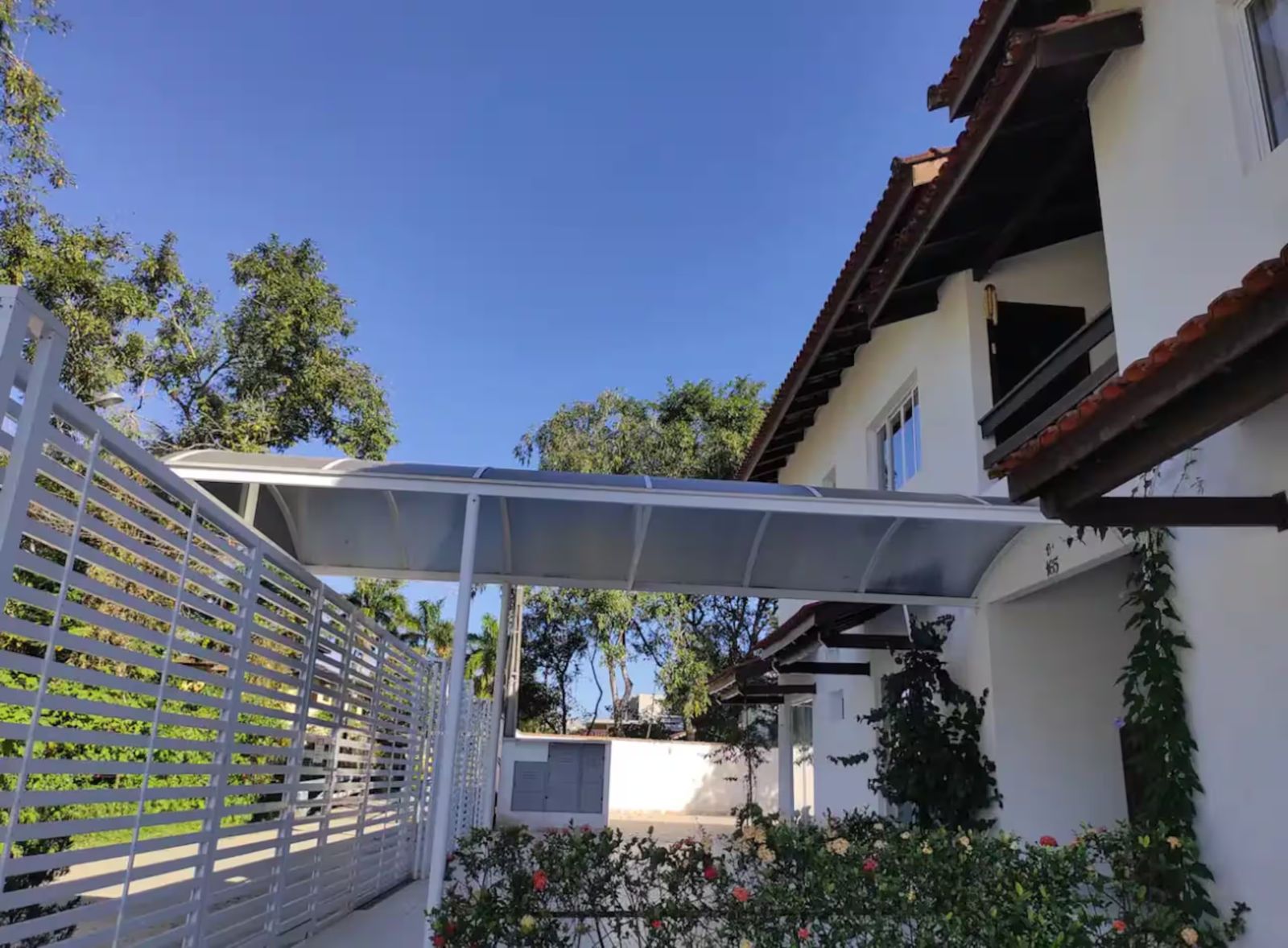 Condomínio de sobrados brancos com telhado colonial e jardim
