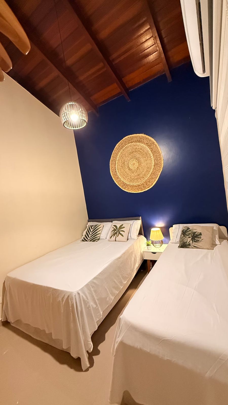 Quarto com parede azul, cama queen e cama de solteiro