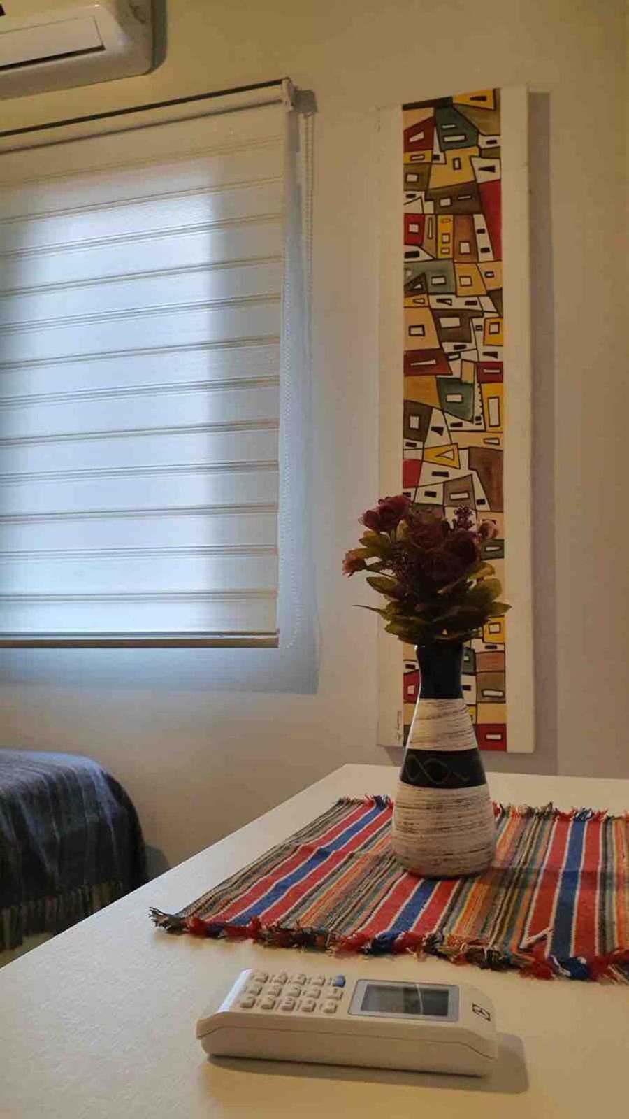Janela com persiana e vaso de flores