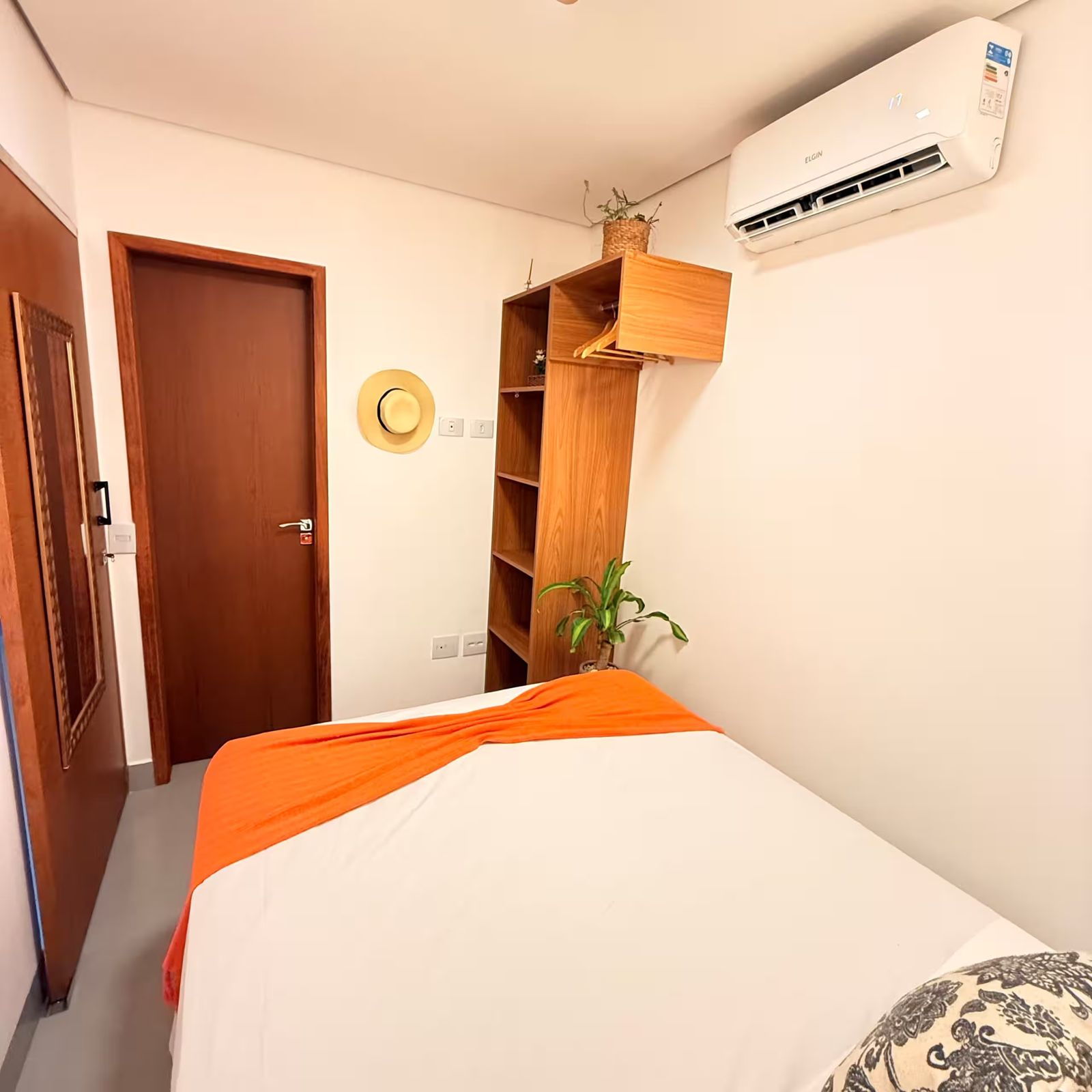 Suíte com cama de casal e manta laranja