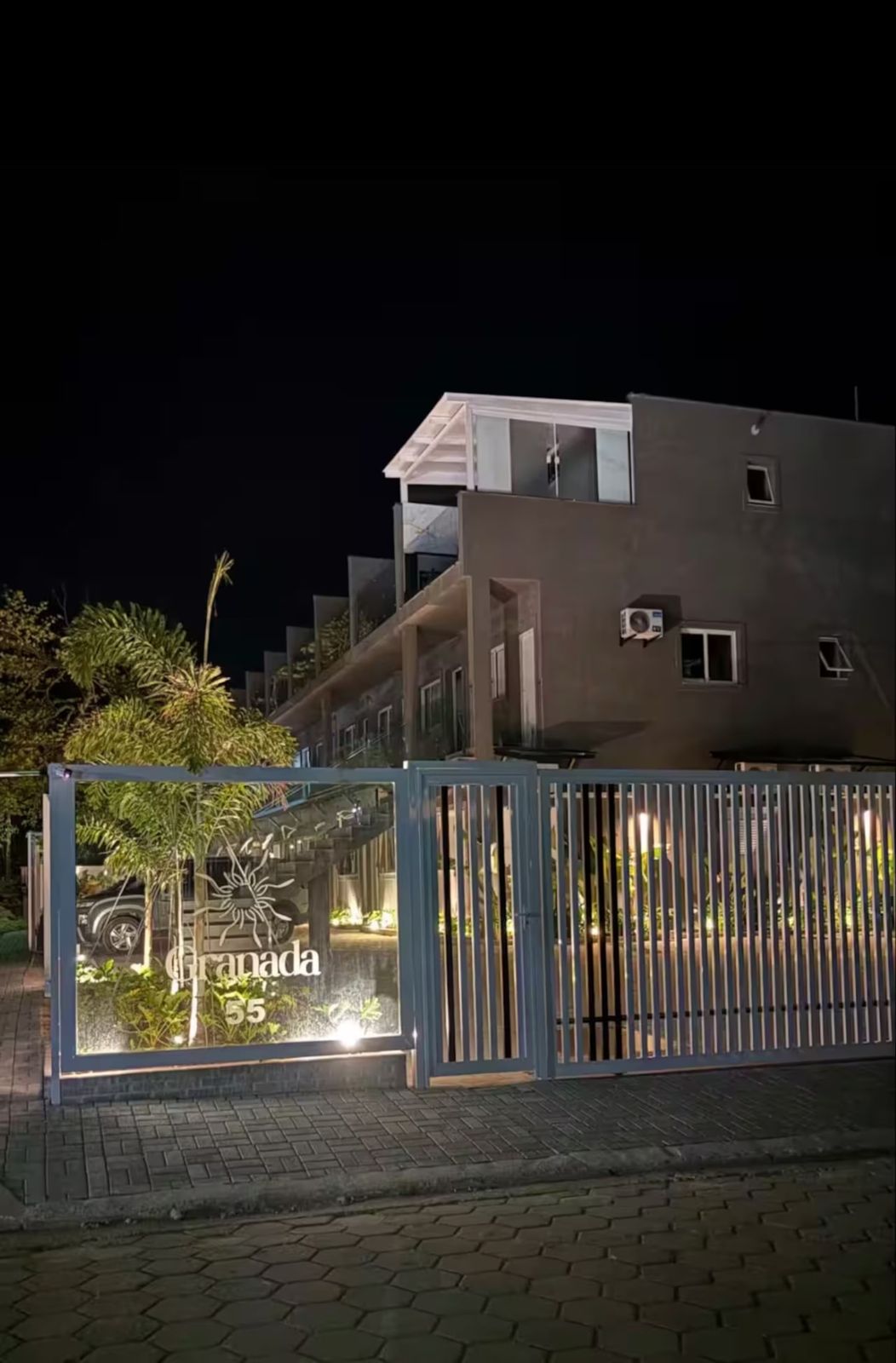 Portão do condomínio iluminado à noite