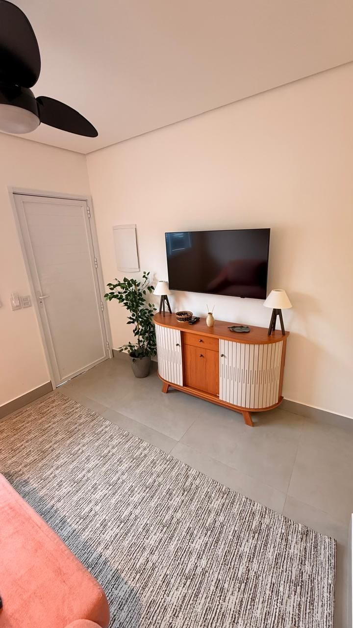 Sala com TV, aparador e porta de entrada
